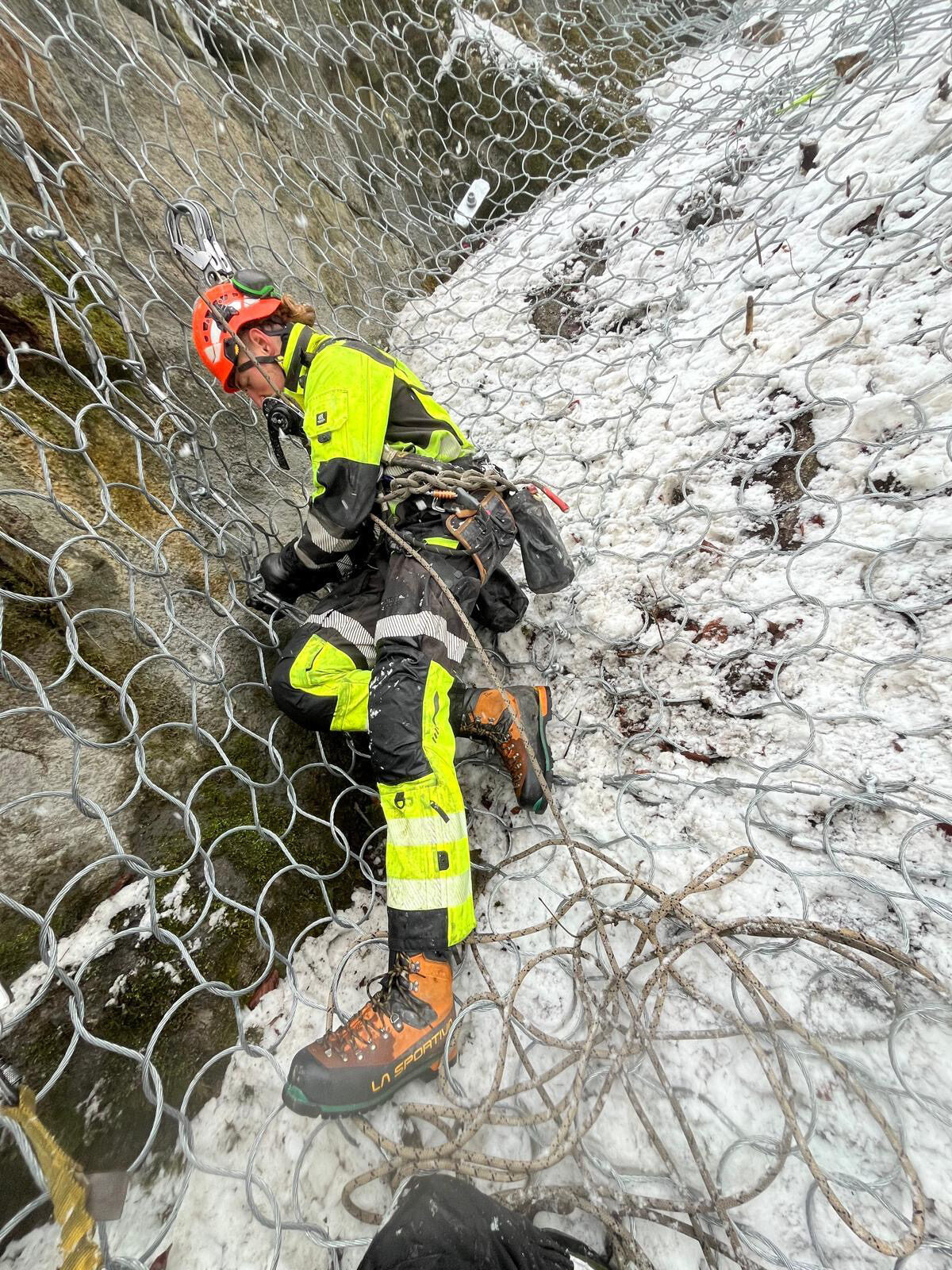 Rope access technician working on a steep rock face in Extreme Access hi-vis gear